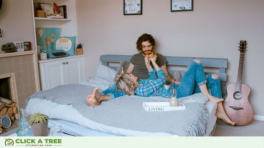 Couple eating pizza on bed.
